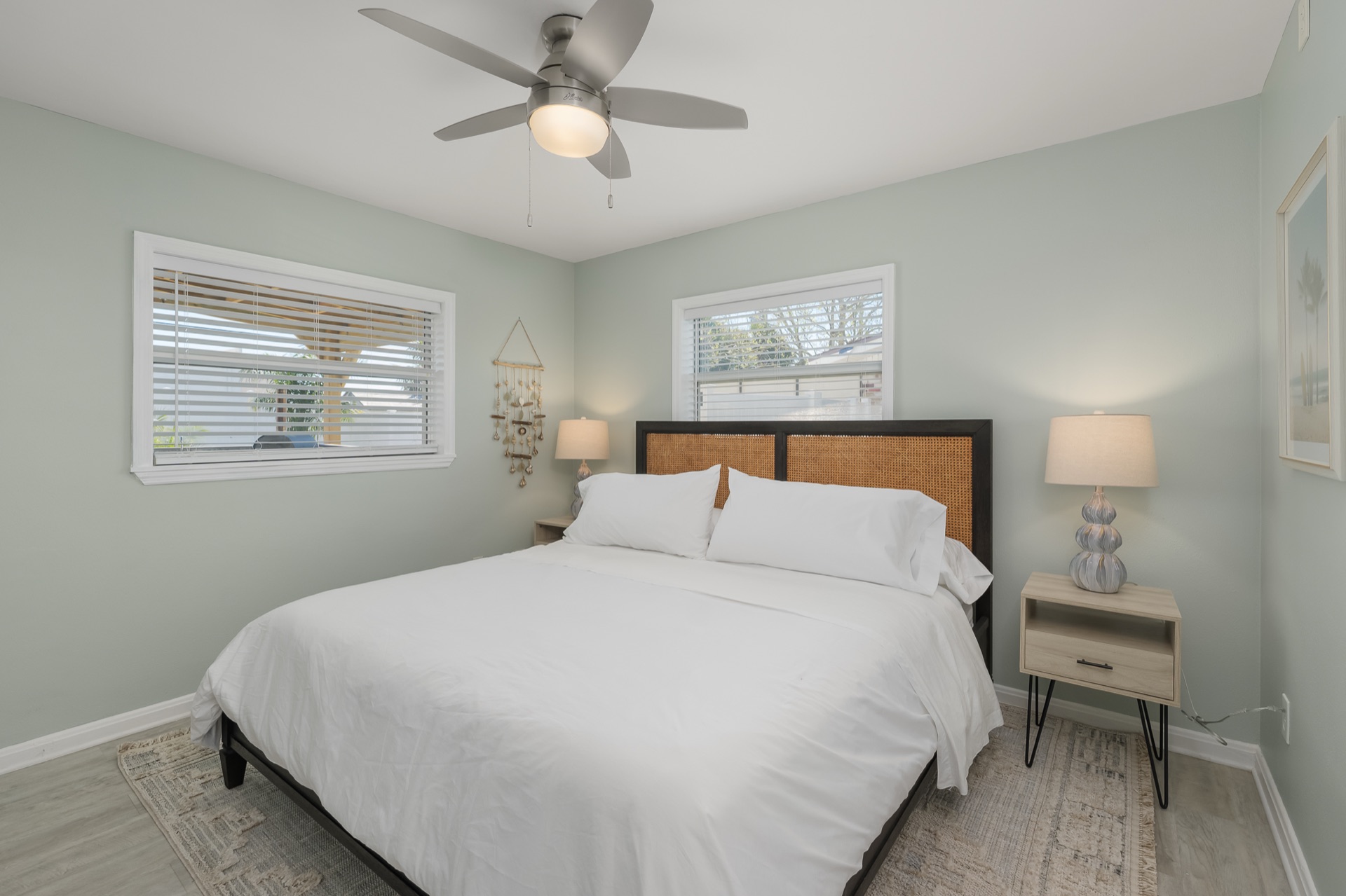 A second bedroom at Shell Yeah with a rattan headboard and calming neutral palette