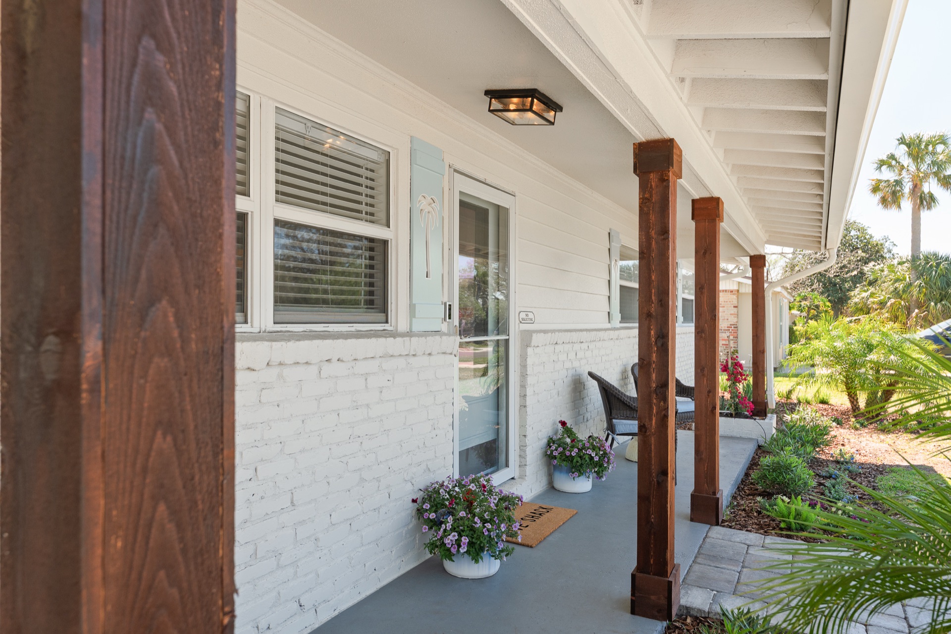 Covered front porch at Shell Yeah with wicker seating and coastal blue shutters