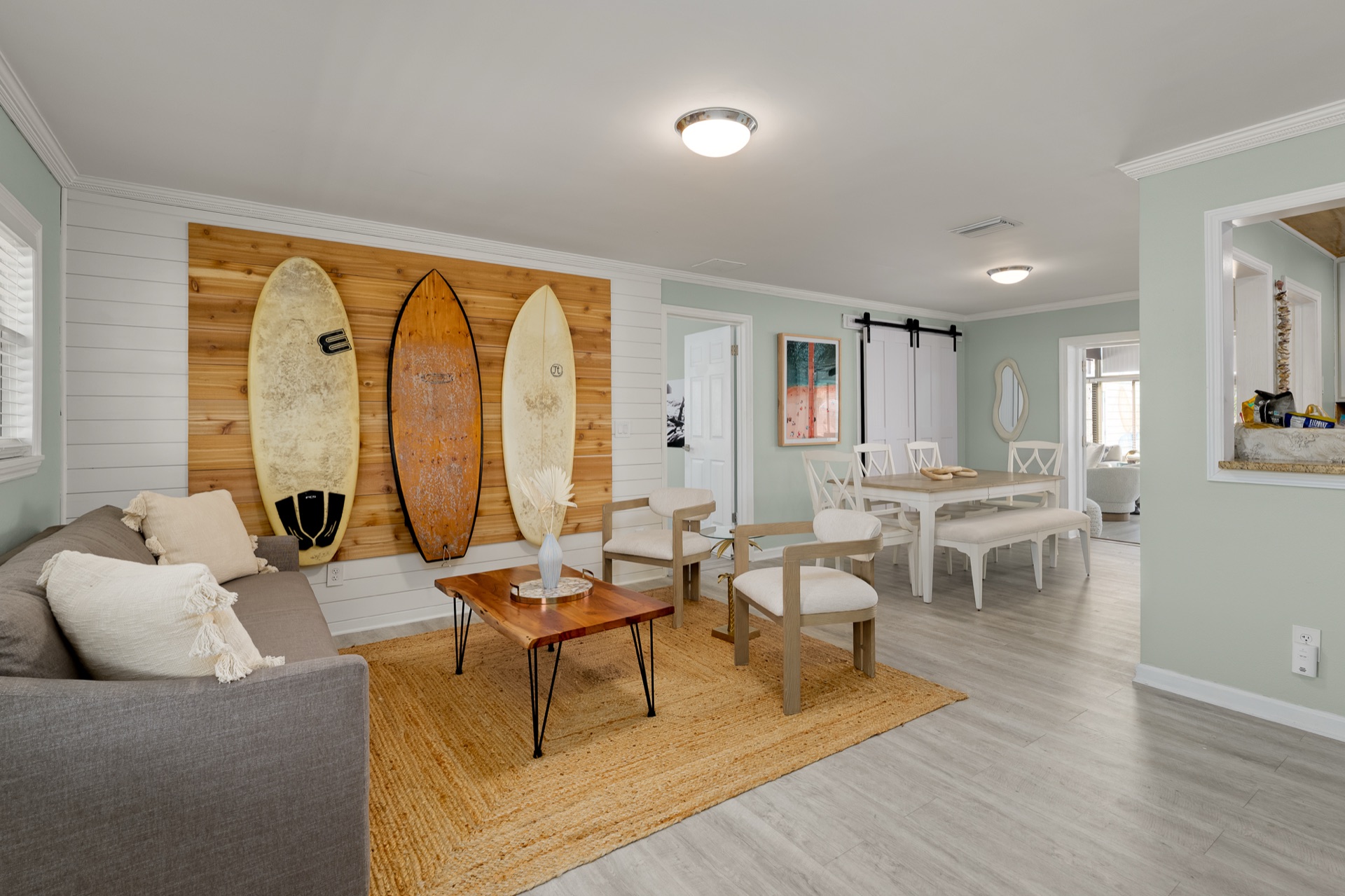 Bright, open living room at Shell Yeah with shiplap walls, surfboard decor, and coastal-modern furniture