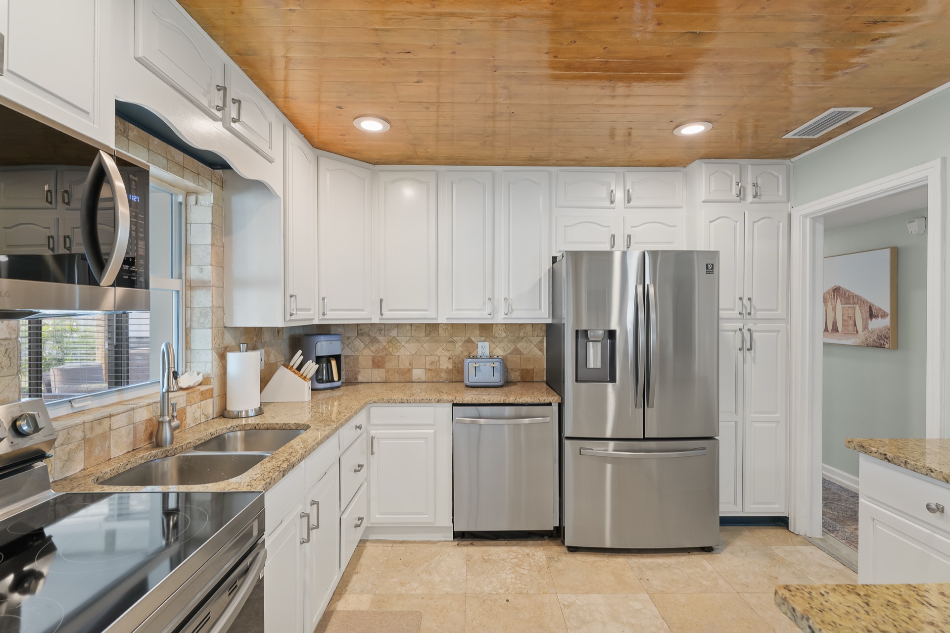 Full kitchen at Shell Yeah with white cabinetry, stainless appliances, and granite counters