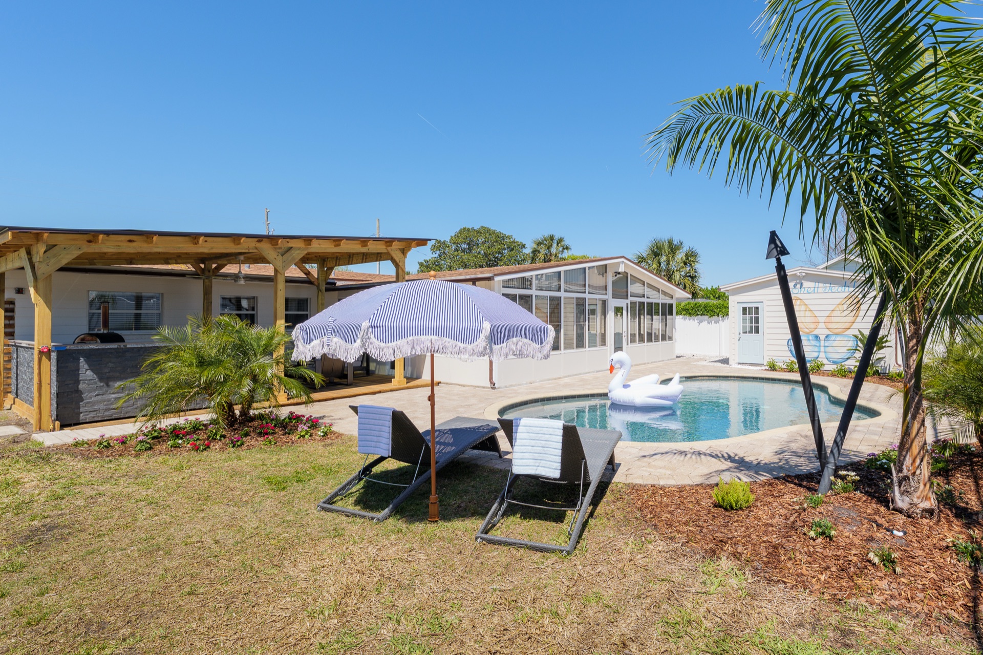 Backyard view at Shell Yeah showing the pool, wellness building, and covered patio