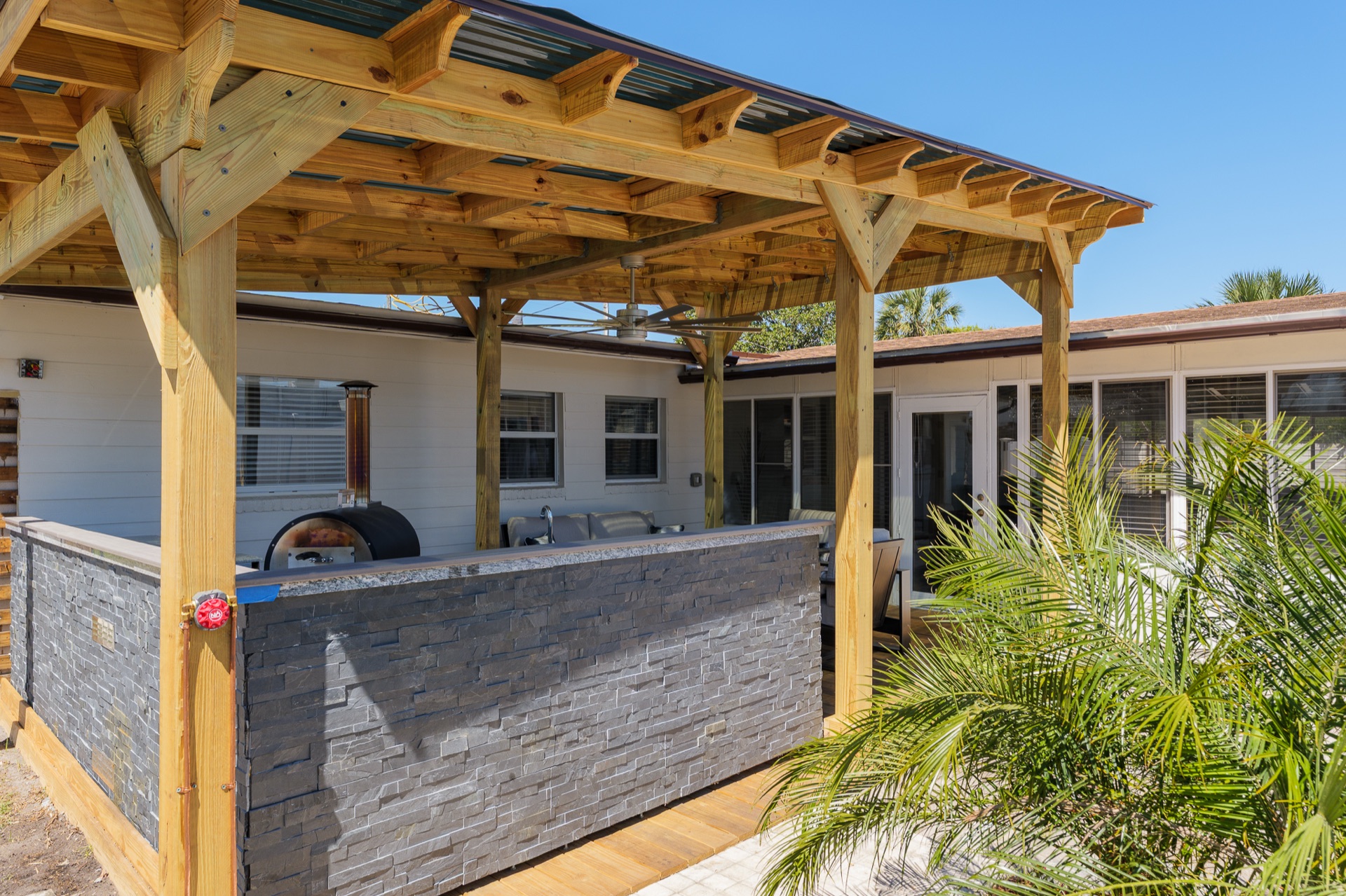 Outdoor kitchen at Shell Yeah with a built-in grill and pizza oven under a covered pergola